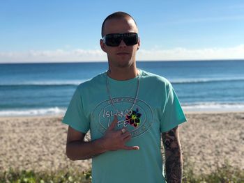 Portrait of man in sunglasses gesturing shaka sign at beach