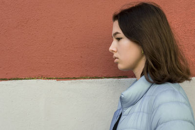 Teen girl profile against a wall outdoors