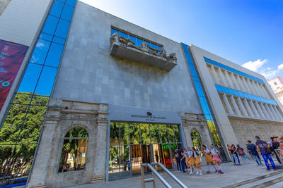 People walking on modern building against sky in city