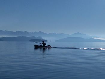 People sailing on sea against clear sky