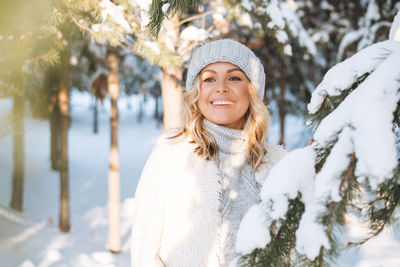 Portrait of smiling young woman standing on snow