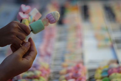 Cropped hands of people holding marshmallow at stall