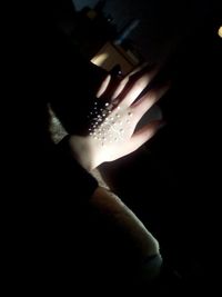 Close-up of hand holding illuminated light over black background