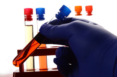 Close-up of hand holding bottle against blue background