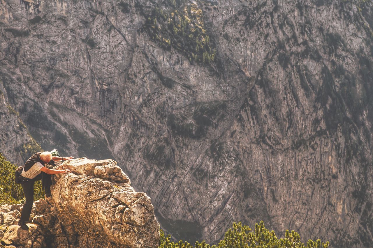 lifestyles, leisure activity, rock - object, men, standing, person, high angle view, mountain, casual clothing, nature, rock formation, tranquility, water, rear view, rock, tranquil scene, beauty in nature, full length