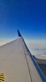Close-up of airplane wing over sea against clear blue sky