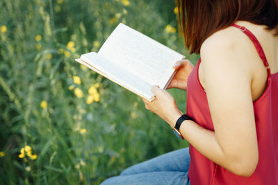 Midsection of woman reading book outdoors