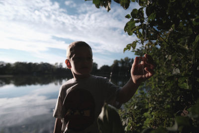 Rear view of boy standing by tree against sky