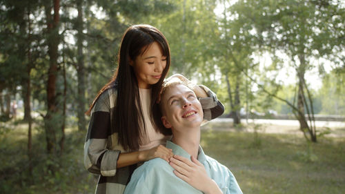 Smiling girlfriend embracing handicapped boyfriend at park