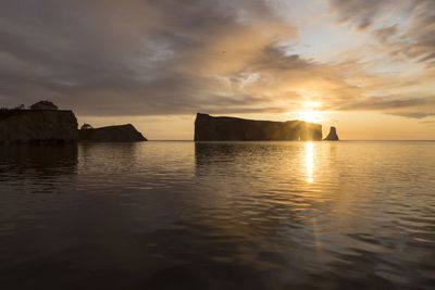 Golden view of the percé village cliffs and famous rock seen during a beautiful summer sunrise