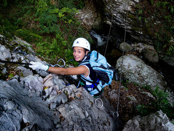 Full length portrait of smiling young woman hanging on rope