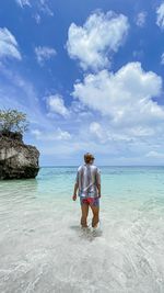 Rear view of man in sea against sky