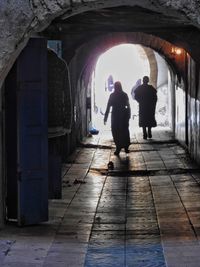 Silhouette people walking in tunnel