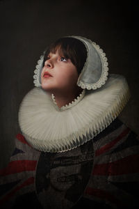 Portrait of young woman wearing hat against black background