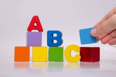 Cropped hand holding toy blocks against white background