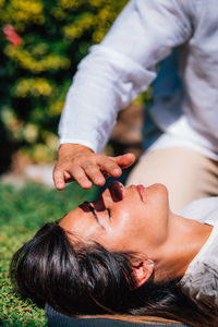 Close-up image of relaxed woman lying with her eyes closed and having reiki healing treatment