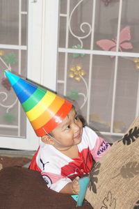 Smiling boy wearing party hat at home