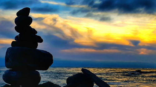 Rear view of silhouette man at beach against sky during sunset