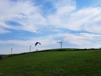 Wind turbines on field against sky