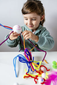 Cute girl holding toy while sitting on table