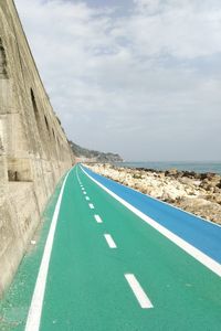 Pedestrian walkway by beach against sky