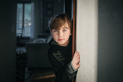 Portrait of young woman looking through window