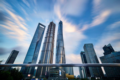 Low angle view of skyscrapers against cloudy sky