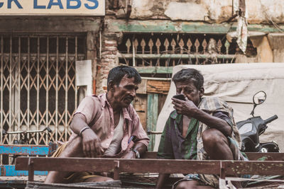Senior men using mobile phone while sitting in city
