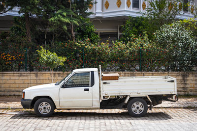 White pickup is parked on the street on a warm summer day against the backdrop of a parking