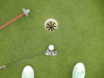 High angle view of canvas shoes and golf club by hole at course