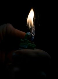 Close-up of hand holding candle against black background