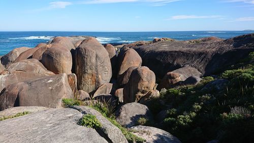 Rocks on shore by sea against sky