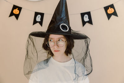 Teenage girl in a witch's hat with a sly look.