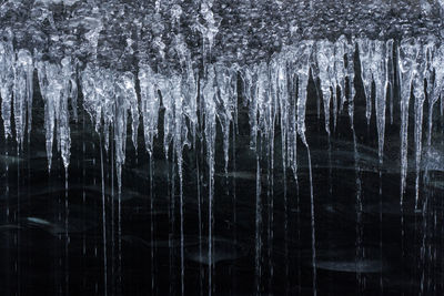 Clean water falling down from icicles inside dark icy cave in vatnajokull national park in iceland