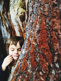 Cute boy leaning on tree trunk