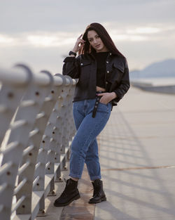 Full length portrait of young woman standing against sky