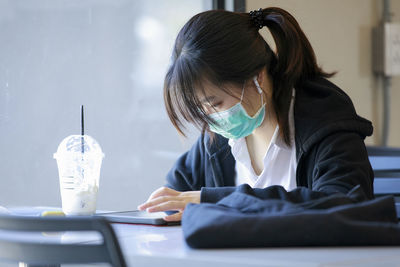 Portrait of young woman using phone while sitting on table