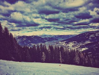 Snow covered landscape against cloudy sky