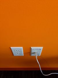 High angle view of electric plug on orange wall