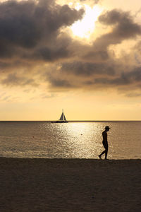 Silhouette man on eagle beach aruba against sky during sunset