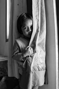 Close-up of girl hiding behind curtain at home