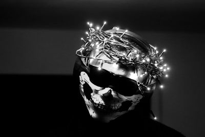 Close-up of man wearing mask with illuminated string light on head