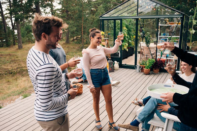 Happy male and female friends raising toast on cottage deck