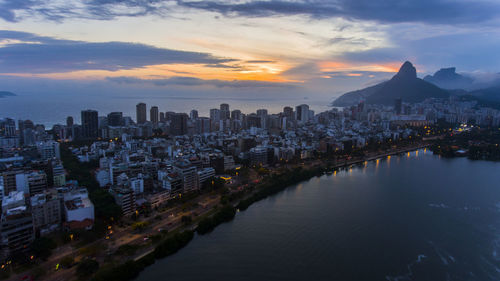 Cityscape by sea against sky during sunset