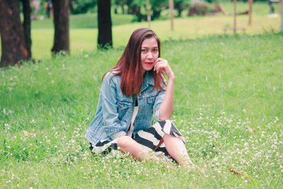 Portrait of young woman sitting on field