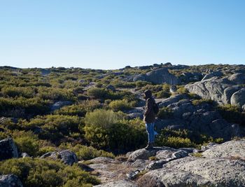 Hiker standing on landscape against clear blue sky