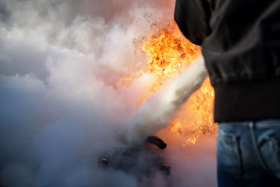 Rear view of man spraying water on fire