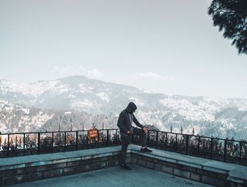 Man standing on railing against mountain