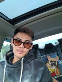 Portrait of young man with dog in car