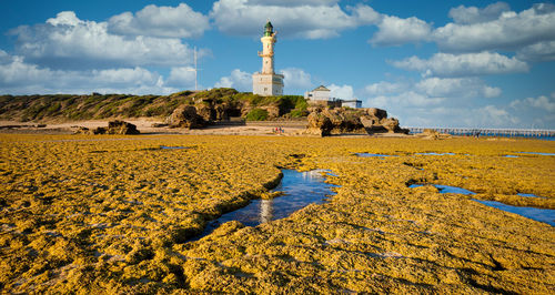 Scenic view of beach and lighthouse against sky. 